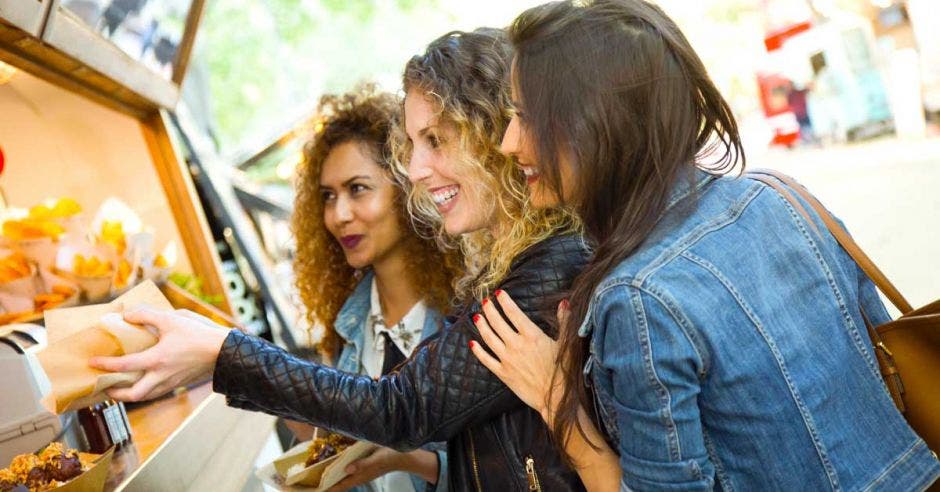 tres mujeres recibiendo la comida de un foodtruck