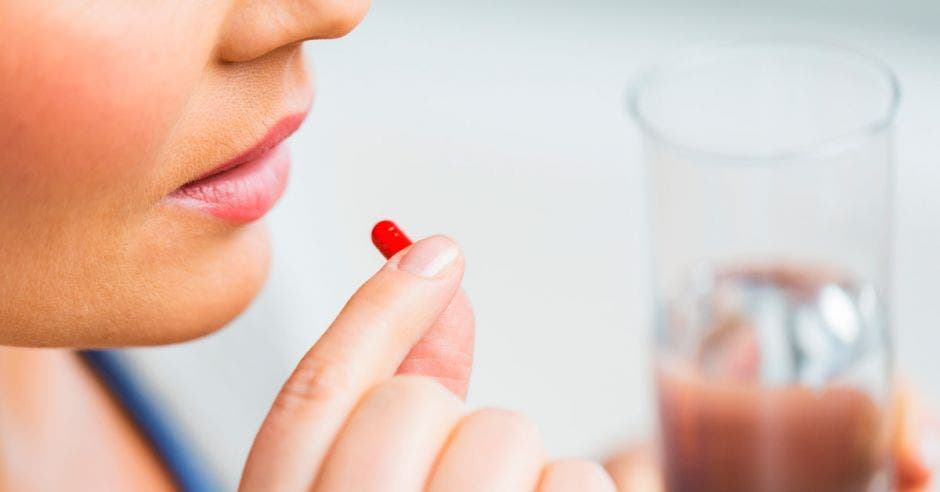 Una mujer tomando una pastilla sin que se le vea el rostro