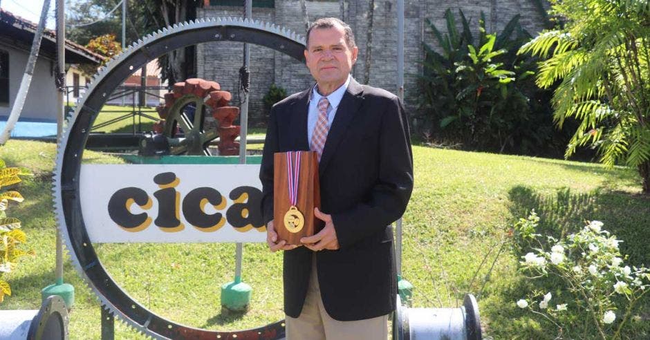 Un señor posa con una medalla frente a las instalaciones de Icafé