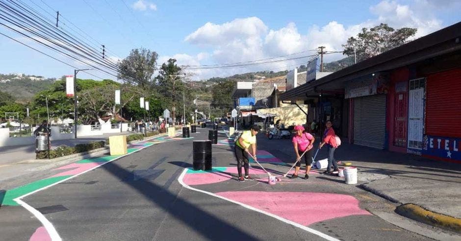 un  grupo de personas pinta una calle de color rosado