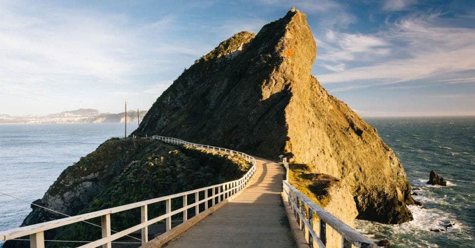 un sendero que conduce a una gran piedra en medio del mar