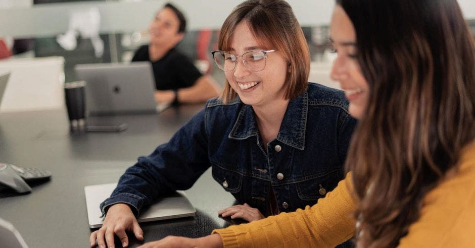 dos mujeres manipulan una computadora en un escritorio