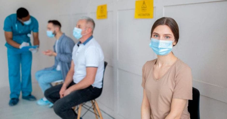 personas en fila esperando a ser vacunadas